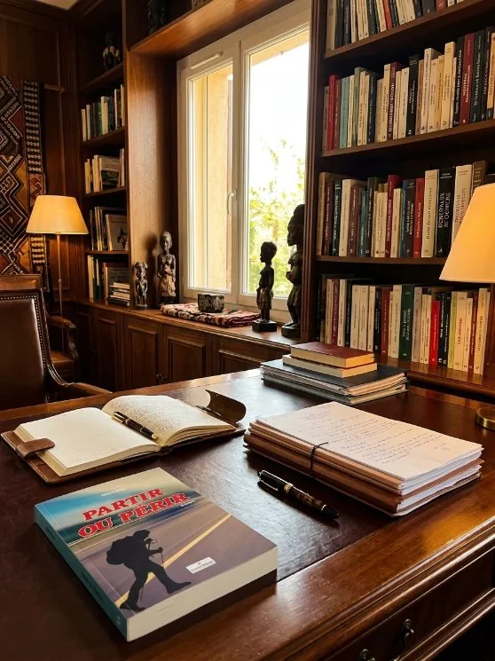 Ouvrage et manuscrit annoté posés sur le bureau du cabinet, à Bamako